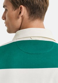 Groen en wit gestreept poloshirt met een zachte stofstructuur, een witte kraag en een subtiele logotag op de hals.