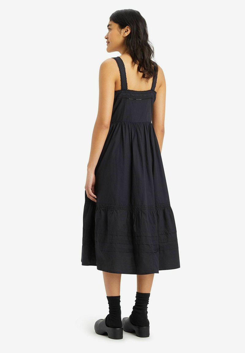Robe midi en coton noir avec un corsage ajusté, des bretelles texturées, une jupe à volants et de délicates accents en dentelle le long de l'encolure.