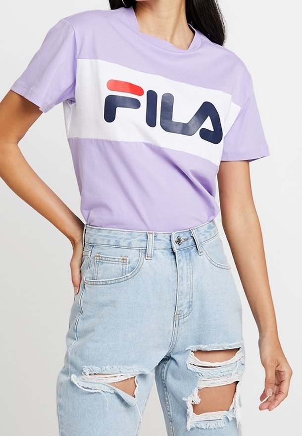 Lilac crewneck T-shirt with white band featuring large black and red "FILA" logo; paired with distressed light blue denim jeans.