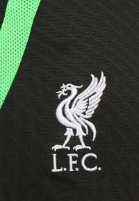 Czarny materiał o teksturowanym wykończeniu ma wyraźny, biały haftowany herb Liverpool Football Club, podkreślony zielonym paskiem z siateczki.