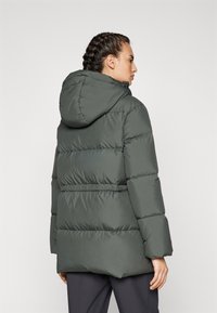 Giubbotto puffer verde con cappuccio, caratterizzato da un design trapuntato, vita elastica e tasche laterali per calore e comfort.
