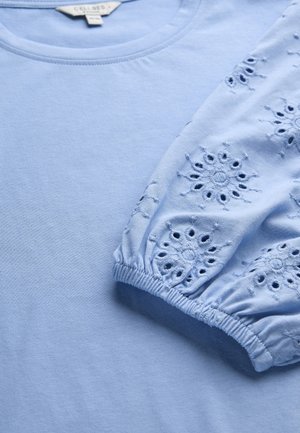 Lichtblauw shirt met lange mouwen en elastische manchetten, voorzien van geborduurde bloemmotieven met uitsnijdingen.