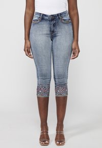 Knielange Denim-Jeans in Hellblau, mit dekorativer Stickerei am Saum und fünf Taschen mit kontrastierenden Nähten.