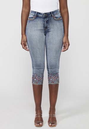 Knee-length denim jeans in light blue, featuring decorative embroidery at the hem and five pockets with contrasting stitching.
