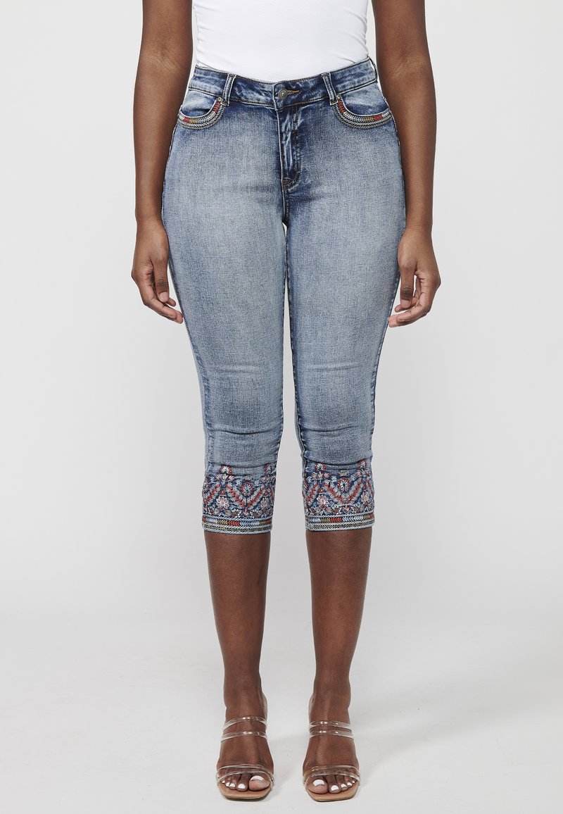 Knielange Denim-Jeans in Hellblau, mit dekorativer Stickerei am Saum und fünf Taschen mit kontrastierenden Nähten.