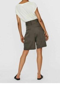 Khaki-shortsit, joissa on räätälöity muotoilu, korkea vyötärö, sivutaskut ja sileä pinta, yhdistettynä kevyeseen, löysään valkoiseen paitoihin.