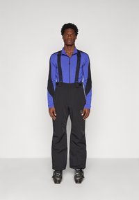 Ski tērps ar zilu augšu ar rāvējslēdzēju, melniem akcentiem un melniem biksēm, teksturēts audums, regulējami siksnas un slēpošanas zābaki.