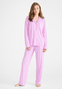 Rosa pyjamas set i lättviktsmaterial, med långa ärmar, en knapp-up skjorta med bröstficka, och löst sittande byxor.