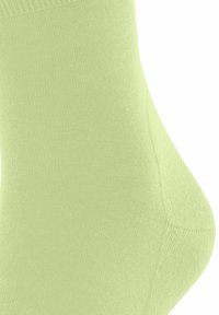 Chaussette de cheville vert clair avec une texture lisse, dotée d'un bord-côte et d'un embout sans couture, mettant en avant un style minimaliste.