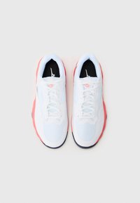 Hvide sports sneakers med en overdel i mesh, lyserøde detaljer på sålen og sort indvendig. Snørebåndene er lyseblå med et struktureret mønster.