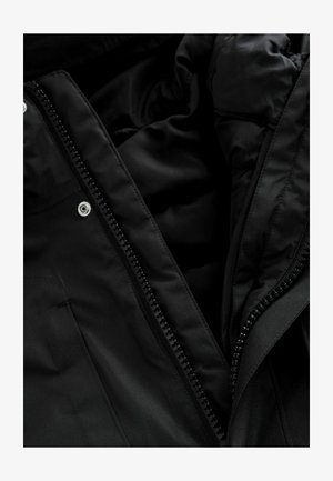 Veste noire isolée avec une fermeture éclair intégrale, présentant une texture lisse, des boutons-pression et une doublure intérieure.