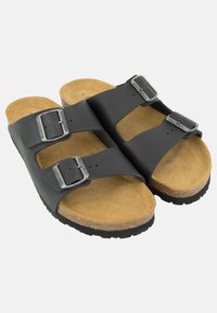 Sandali in pelle nera con due cinturini regolabili, fibbie in argento e una soletta in sughero. Suola in gomma con grip texturizzato. Soletta color marrone chiaro.