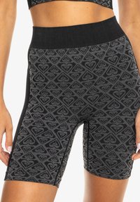 Schwarze, gemusterte Biker-Shorts mit einem breiten, glatten Bund und einem geometrischen Design in Grautönen. Aus einem dehnbaren Stoff gefertigt.