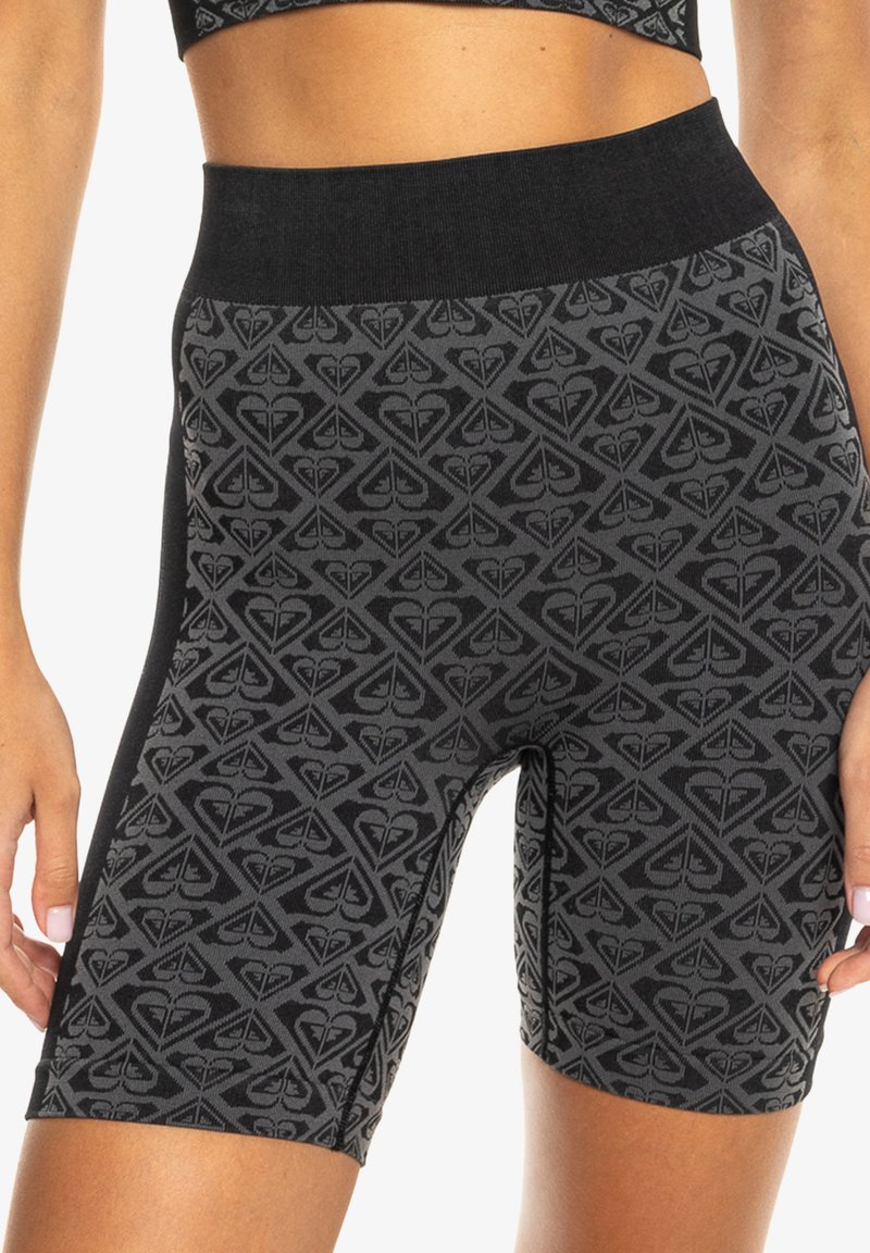 Schwarze, gemusterte Biker-Shorts mit einem breiten, glatten Bund und einem geometrischen Design in Grautönen. Aus einem dehnbaren Stoff gefertigt.