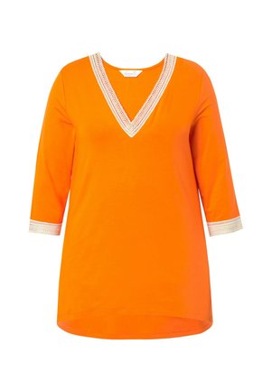 Oranje tuniek met een V-hals en driekwart mouwen, voorzien van een textuur witte rand langs de halslijn en de mouwzoom. Glad materiaal.
