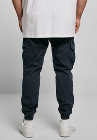 Marinkålsbyxor med elastiska muddar, sidfickor och en avslappnad passform, i kombination med vita sneakers och en lös vit T-shirt.