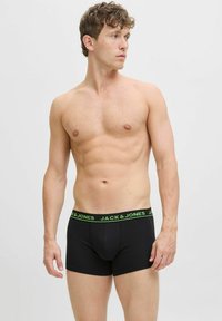 Schwarze Boxershorts mit einem grünen Bund, der das Branding "JACK & JONES" trägt. Der Stoff wirkt glatt und elastisch.