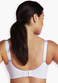 Vit bh med breda axelband, ribbad textur och hak- och ögonslås bak. Slät tyg med minimala detaljer av hårdvara.