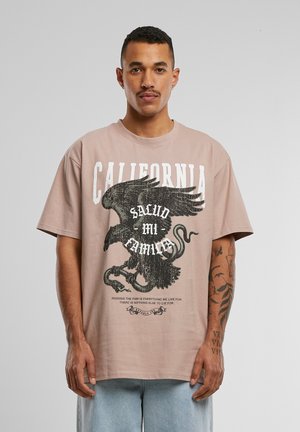 Oversized beige t-shirt featuring a graphic eagle print with text. Short sleeves, crew neck, made from soft cotton material.