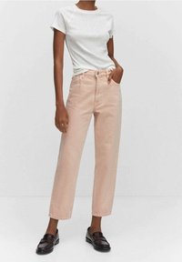 Jean taille haute rose clair à coupe droite, associé à un t-shirt gris ajusté et des mocassins noirs. Le matériau semble être un mélange de coton.