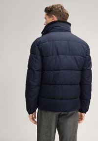 Giacca puffer blu navy con colletto alto, design trapuntato e polsini elastici; presenta un morbido rivestimento interno per un calore extra.