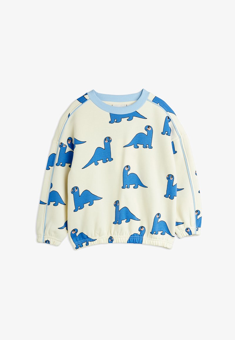 Gaišas krēms krēklis ar rotaļīgu zilu dinozauru rakstu. Riebēti piedurkņu un kakla gali, brīvs griezums un mīksta tekstūra.