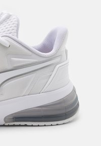 Bílé sportovní boty se síťovinou a syntetickým svrškem, s polstrovaným límcem, šedými detaily a silnou průhlednou podrážkou.