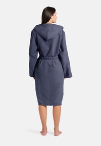 Tmavě modrý župan s kapucí, vyrobený z měkké látky, dlouhé rukávy, v pase stahovaný páskem, délka do kolen, hladká textura.