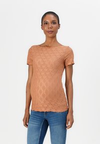 Lys brun teksturert t-skjorte med diamantmønster, korte ermer og rund hals, parret med blå jeans.