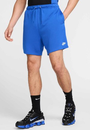Pantalones cortos deportivos azules con un acabado texturizado, cinturilla con cordón y bolsillos laterales. Presenta un pequeño logo blanco de Nike en el dobladillo.
