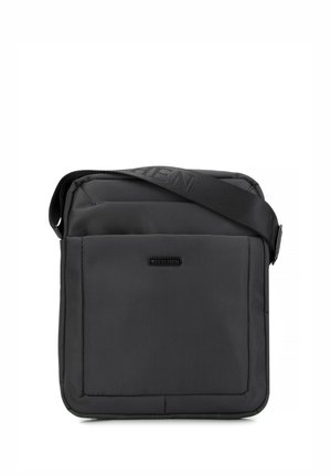 Bolsa mensajera negra hecha de tela duradera. Forma cuadrada con un bolsillo frontal, correa ajustable y logo de la marca en relieve en la tapa.