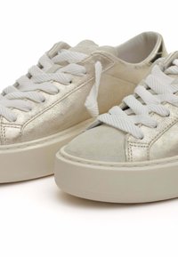 Baskets argentées métalliques avec une finition en cuir suédé, des lacets blancs et une semelle épaisse crème. Elles présentent des panneaux lisses et texturés.