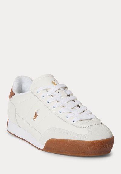 Fehér alacsony szárú sportcipő barna velúr sarokrésszel és gumitalppal, fehér fűzőkkel, valamint Polo Ralph Lauren logóval az oldalon és a nyelven.