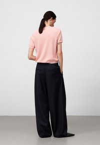 Corto top rosa a maniche corte e pantaloni larghi blu navy scuri. Tessuto morbido, vestibilità rilassata, con sottili polsini sulle maniche e tasche posteriori.