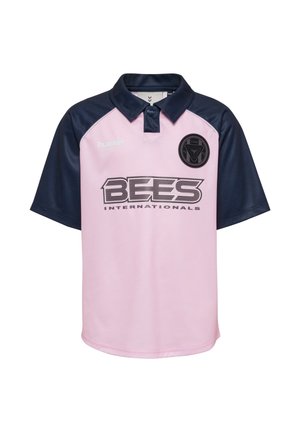 Lyserød polo-shirt med korte ærmer og en marineblå krave, der har en "BEES INTERNATIONALS"-logo i fed sort skrift og subtile teksturdetaljer.