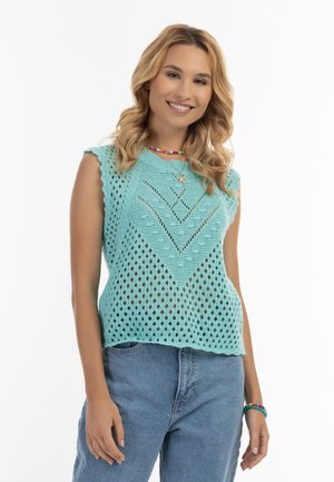 Top tricotat de culoare turcoaz deschis, cu model din dantelă, margini ondulate și o croială lejeră. Asortat cu blugi blue.