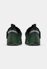 Groene sportieve schoenen met een glad synthetisch bovenwerk, textuurelementen, reflecterende strepen en een gevoerde zwarte binnenkant. Rond ontwerp van de hak.