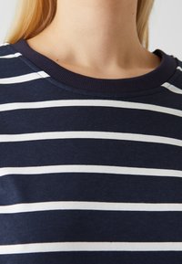 Tricou bleumarin cu dungi albe orizontale, guler rotund, guler ribflat și textură de țesătură moale.