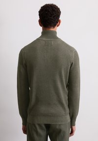Olivgrüner, gestrickter Pullover mit hohem Kragen, gerippten Bündchen und Saum, der ein strukturiertes Muster und eine durchgehende einfarbige Gestaltung aufweist.
