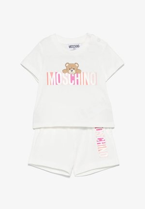 Completo bianco a due pezzi composto da una camicia a maniche corte con una grafica di un orso e il testo "MOSCHINO", abbinato a pantaloncini coordinati. Tessuto morbido.