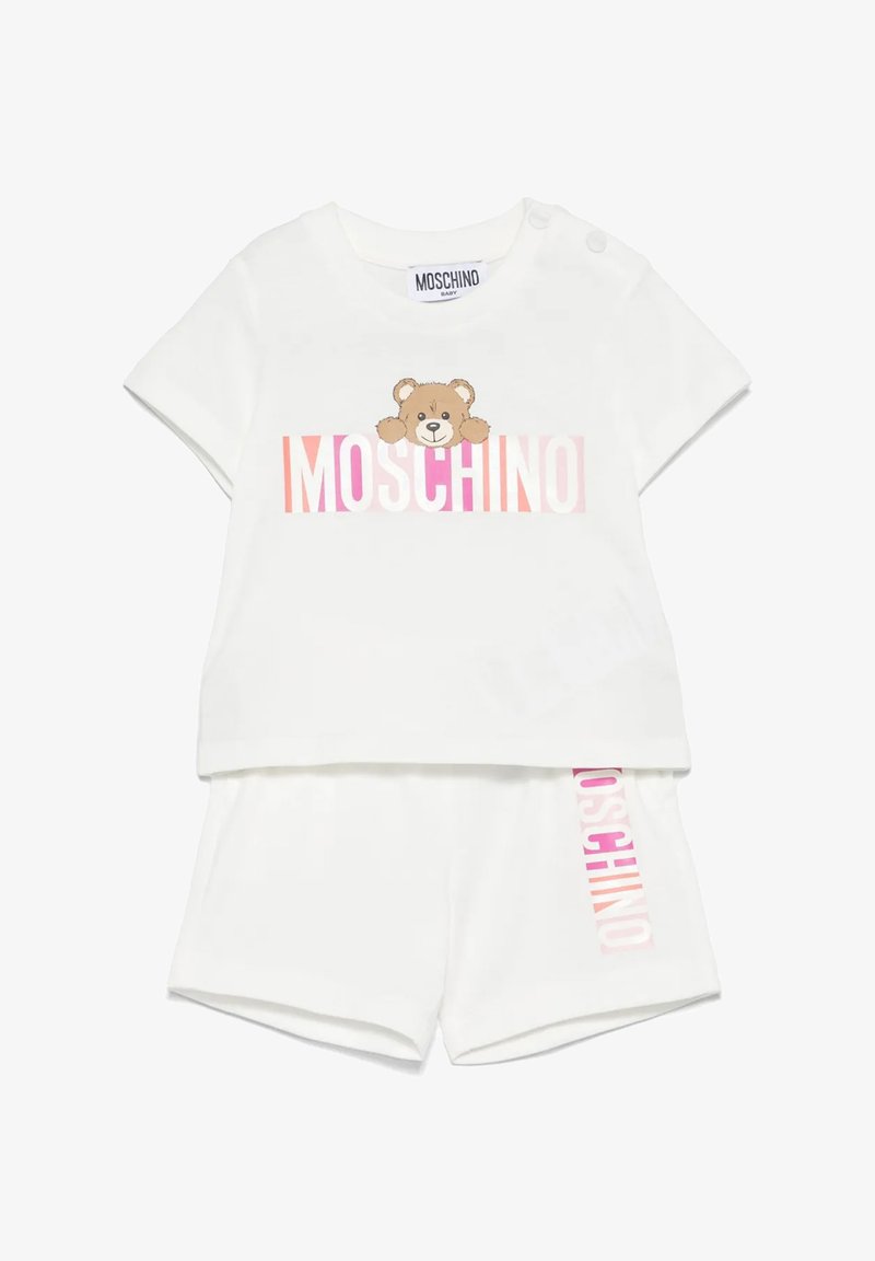 Completo bianco a due pezzi composto da una camicia a maniche corte con una grafica di un orso e il testo "MOSCHINO", abbinato a pantaloncini coordinati. Tessuto morbido.