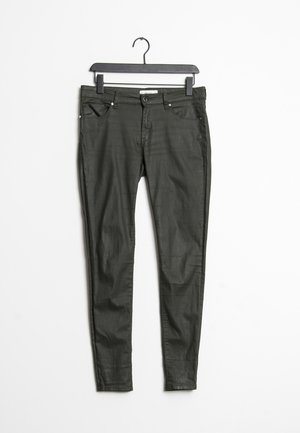 Jean skinny vert foncé en tissu léger, avec une fermeture à bouton sur le devant, cinq poches et un léger délavage le long des jambes.