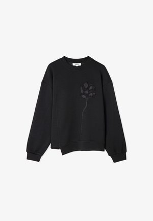 Zwarte longsleeve met geribbelde manchetten en zoom, met een getextureerde zwarte bloemenborduursel op de linkerborst.