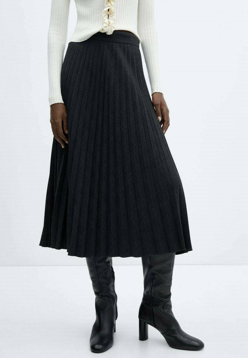 Falda midi negra plisada con una tela texturizada, combinada con botas negras hasta la rodilla. La cintura es lisa y ajustada para un ajuste cómodo.