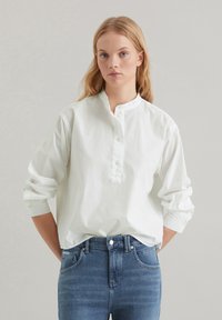 Witte, lange mouwen overhemd met een mandarin kraag, gemaakt van katoen, gecombineerd met hoogwaisted blauwe denim jeans.