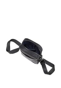 Črna torbica čez telo s teksturirano sprednjo stranjo, zadrgo in nastavljivim trakom. Notranjost ima temno enobarvno podlogo. Kompaktna in pravokotna zasnova.