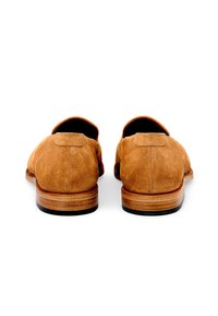 Mocassini in pelle scamosciata marrone con una texture liscia, forma arrotondata e design minimalista. Presentano una suola in pelle cucita e dettagli sul retro.