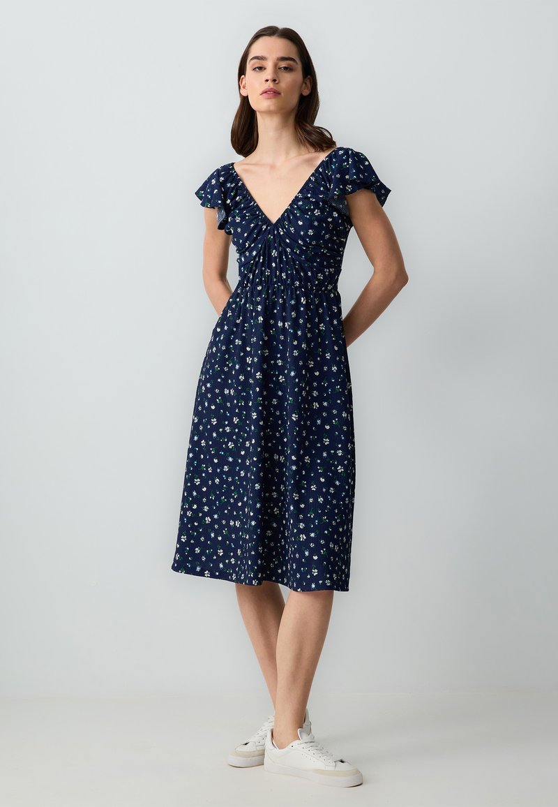 Marineblaues Kleid mit V-Ausschnitt, kurzen, rüschierten Ärmeln und floralem Muster. Verfügt über gerafftes Material an der Brust und einen knielangen A-Linien-Schnitt.