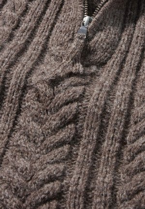 Bruine gebreide trui met een dikke, gestructureerde patroon dat verheven vlechten bevat en een ritsluiting bij de hals. Zachte, warme stof.