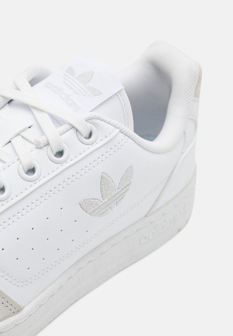 Witte leren sneaker met geperforeerd ontwerp, textuuraccenten en logo. Heeft platte veters en een rubberen zool met ingedrukte branding.